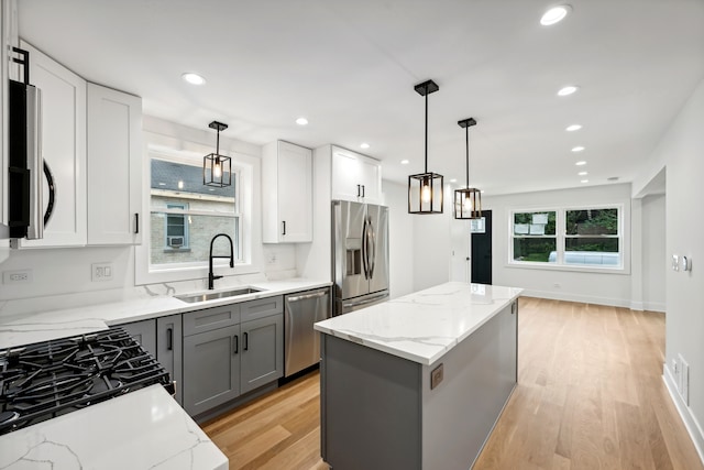 kitchen with light stone counters, stainless steel appliances, light hardwood / wood-style flooring, and sink