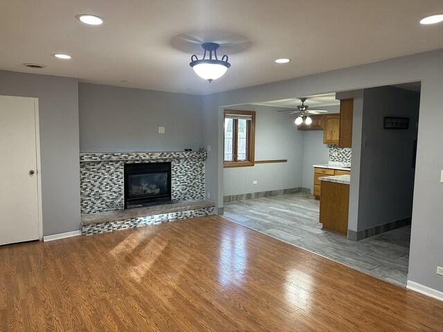 unfurnished living room featuring light hardwood / wood-style flooring, ceiling fan, and a fireplace