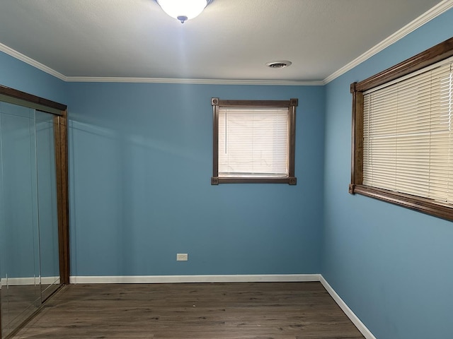 unfurnished bedroom featuring dark wood finished floors, visible vents, and ornamental molding
