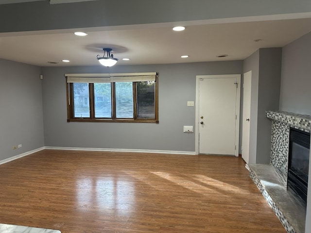 unfurnished living room featuring recessed lighting, a glass covered fireplace, and wood finished floors