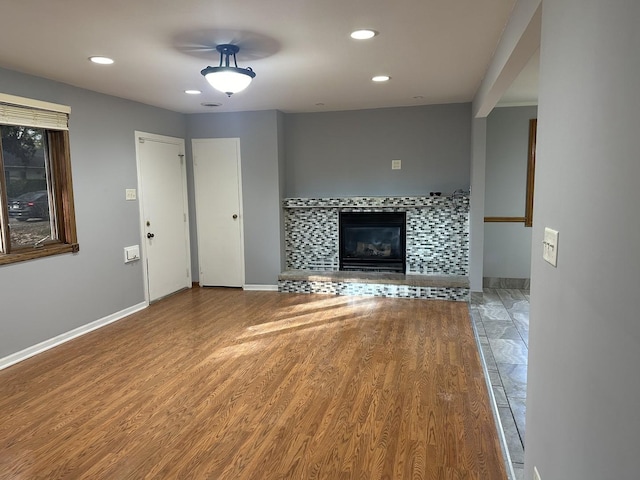 unfurnished living room featuring a tile fireplace, wood finished floors, and recessed lighting