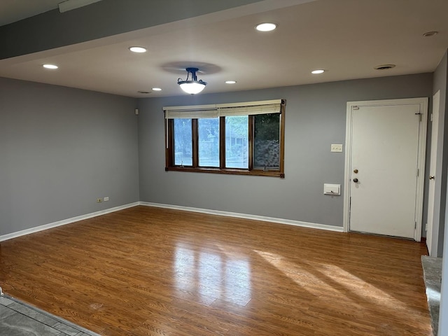 unfurnished room featuring baseboards, wood finished floors, and recessed lighting