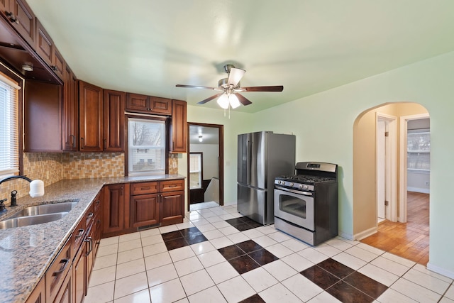 kitchen featuring sink, light tile patterned floors, appliances with stainless steel finishes, light stone counters, and decorative backsplash