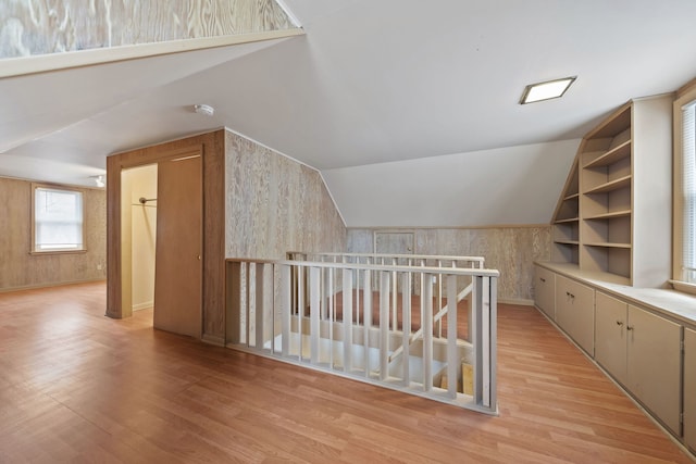 bonus room featuring vaulted ceiling, built in features, and light wood-type flooring