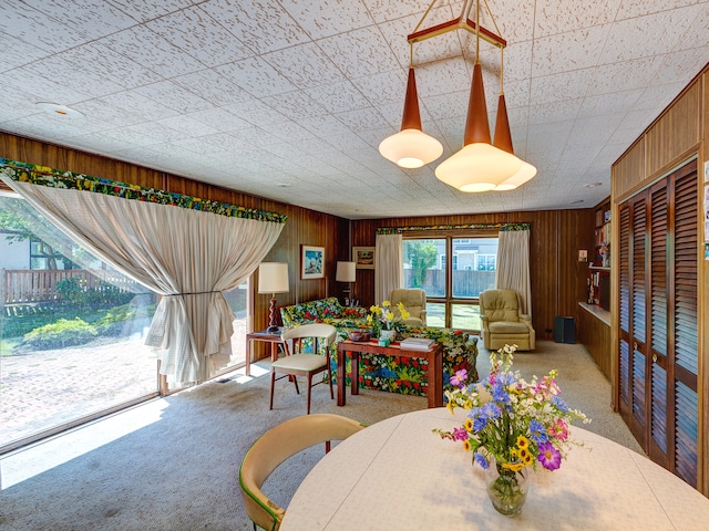 carpeted dining room featuring wood walls