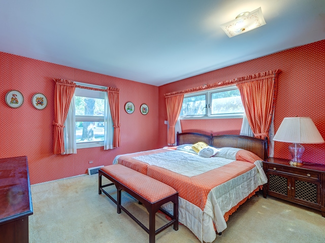 bedroom with light colored carpet and multiple windows