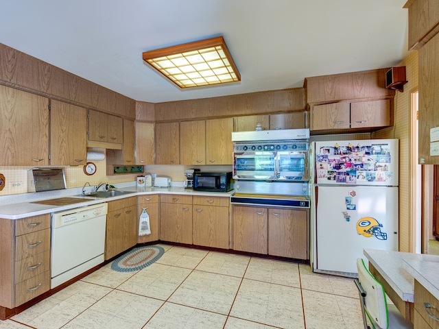 kitchen featuring white appliances, tasteful backsplash, and sink