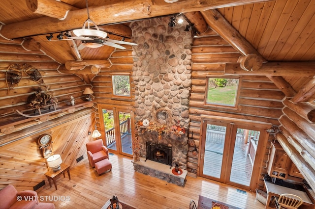 unfurnished living room featuring french doors, wood ceiling, hardwood / wood-style flooring, rustic walls, and a fireplace