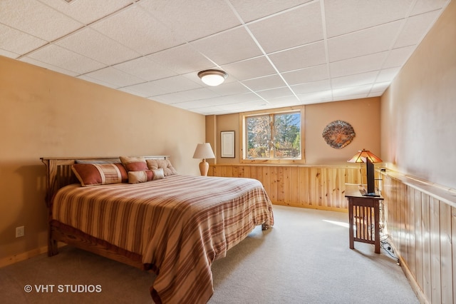 bedroom with carpet, a paneled ceiling, and wooden walls