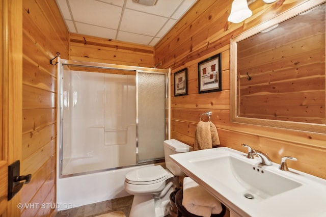 full bathroom with enclosed tub / shower combo, toilet, a paneled ceiling, wooden walls, and sink