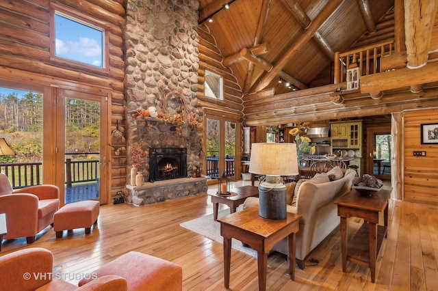 living room featuring a stone fireplace, high vaulted ceiling, and wood-type flooring