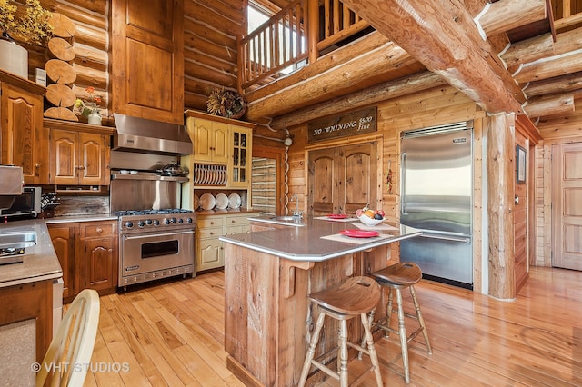 kitchen with extractor fan, a kitchen island with sink, high quality appliances, and log walls