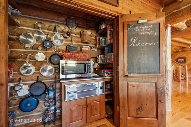 kitchen with light hardwood / wood-style floors, wooden walls, and log walls