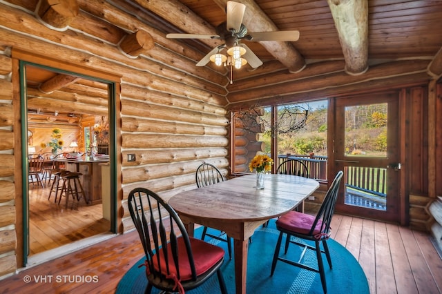 dining area with wood-type flooring, ceiling fan, and log walls