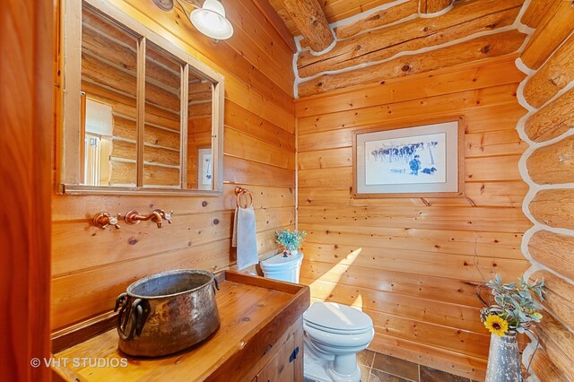 bathroom with tile patterned floors, vanity, wooden walls, and toilet