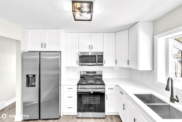 9036 Walnut Ave, Franklin Park, IL 60131 - kitchen featuring appliances with stainless steel finishes, a sink, white cabinets, and decorative backsplash