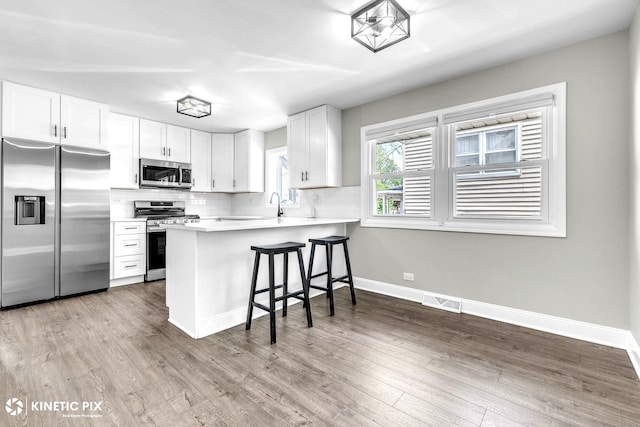 9036 Walnut Ave, Franklin Park, IL 60131 - kitchen featuring stainless steel appliances, backsplash, a peninsula, a kitchen breakfast bar, and white cabinets