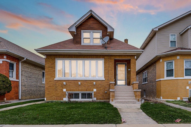 bungalow-style home featuring brick siding and a yard