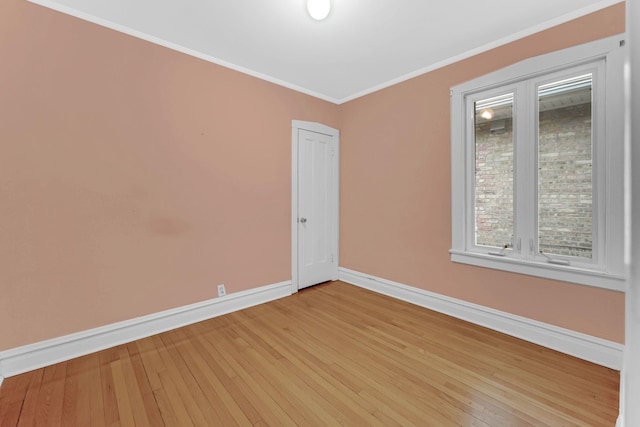 spare room featuring ornamental molding, light wood-style flooring, and baseboards