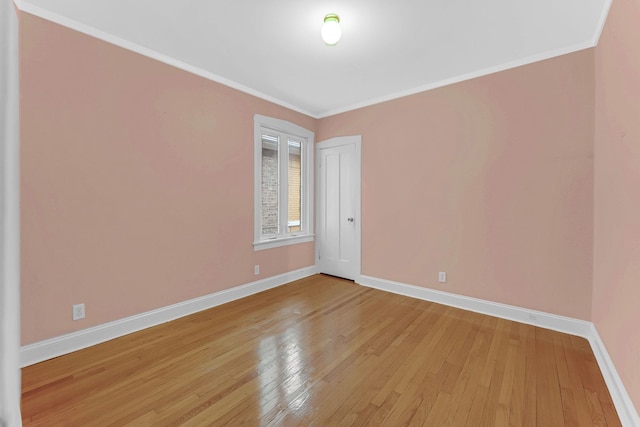 unfurnished room featuring baseboards, light wood-style floors, and crown molding