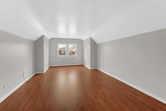 additional living space featuring visible vents, baseboards, vaulted ceiling, and wood finished floors