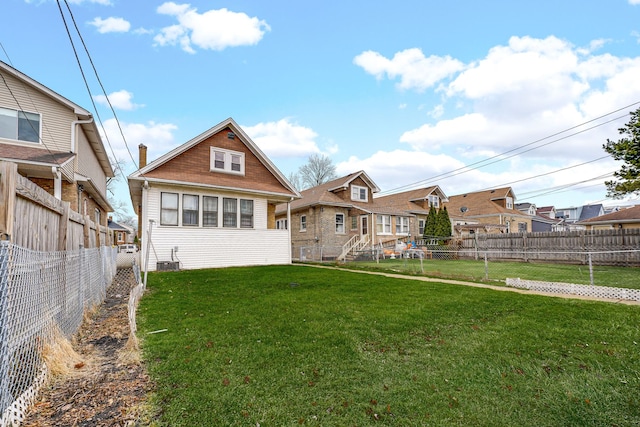 rear view of house with a lawn, a fenced backyard, and a residential view