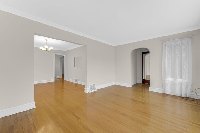 spare room with visible vents, baseboards, arched walkways, ornamental molding, and light wood-style floors