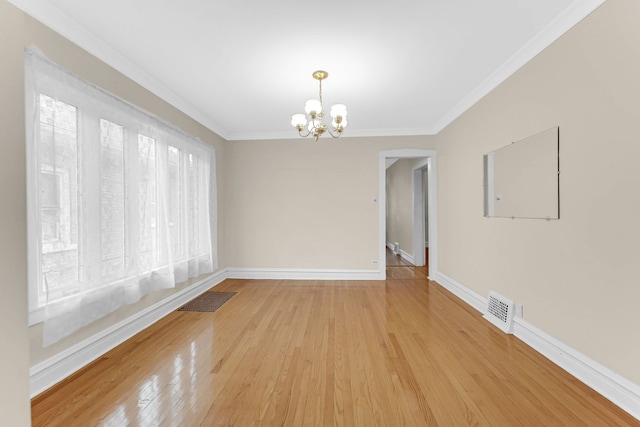 spare room with baseboards, light wood finished floors, visible vents, and crown molding