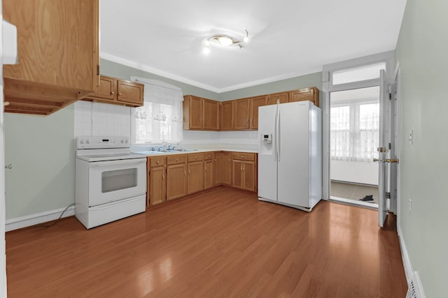 kitchen featuring white appliances, light wood finished floors, decorative backsplash, light countertops, and a sink