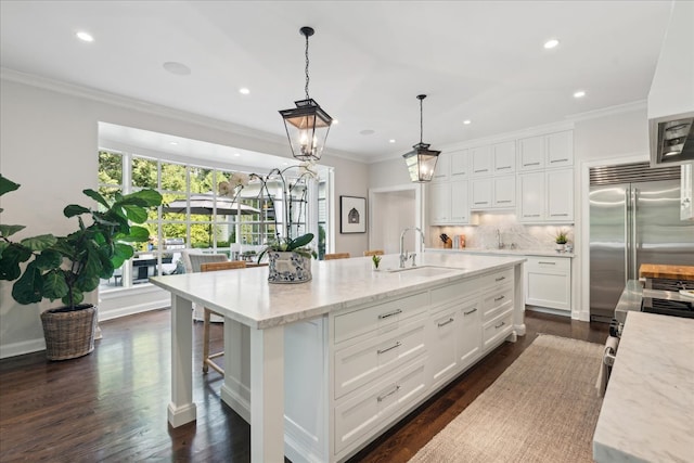 kitchen featuring sink, a spacious island, hanging light fixtures, built in refrigerator, and dark hardwood / wood-style floors