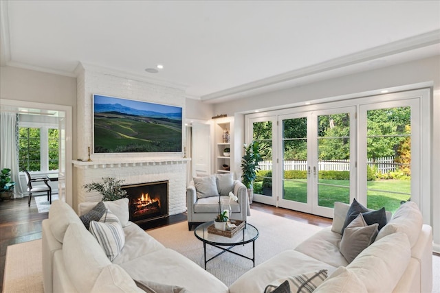 living room featuring a wealth of natural light, crown molding, a brick fireplace, and light wood-type flooring