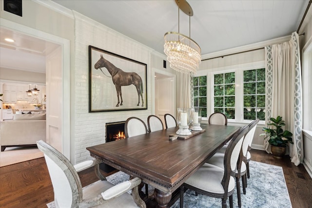 dining room with a notable chandelier, ornamental molding, dark hardwood / wood-style flooring, and a brick fireplace