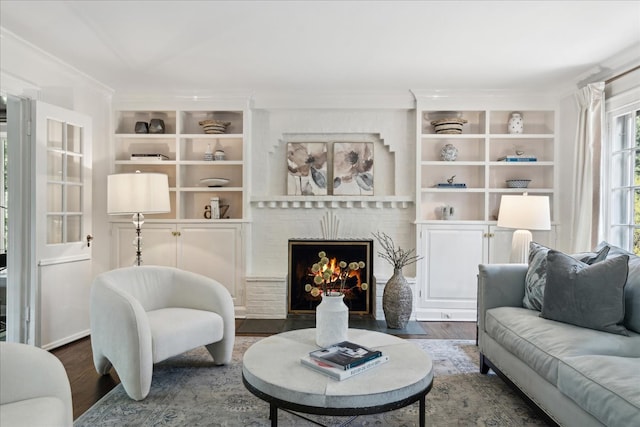 living room featuring crown molding, hardwood / wood-style flooring, a fireplace, and built in shelves