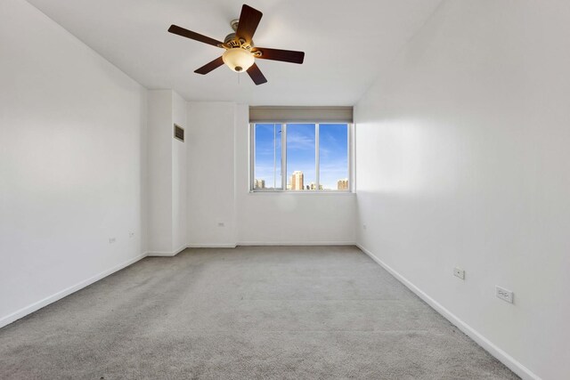 spare room with ceiling fan and light colored carpet