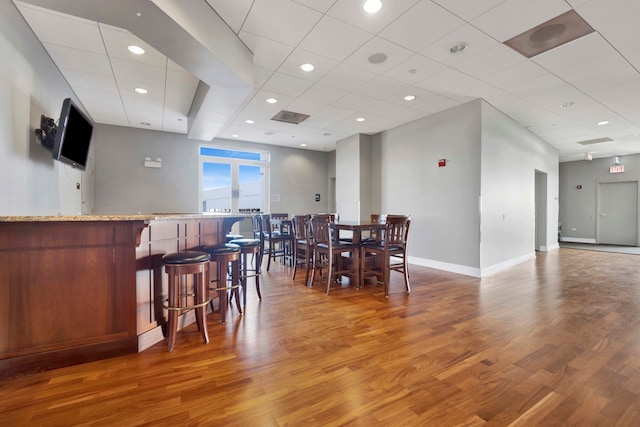 dining area featuring a drop ceiling and hardwood / wood-style flooring