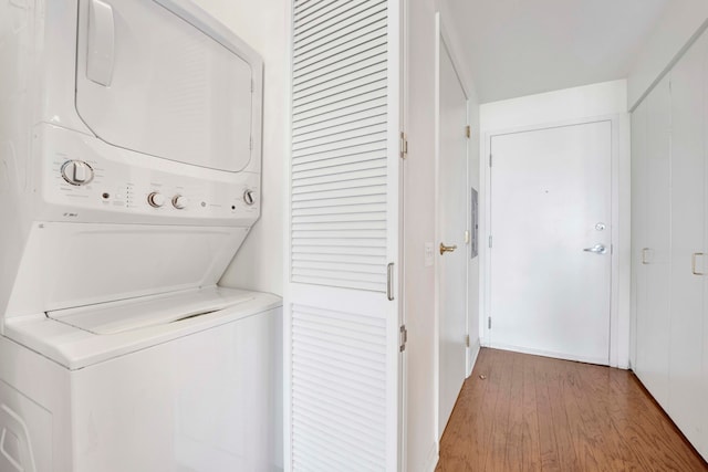 laundry room with light wood-type flooring and stacked washer and dryer