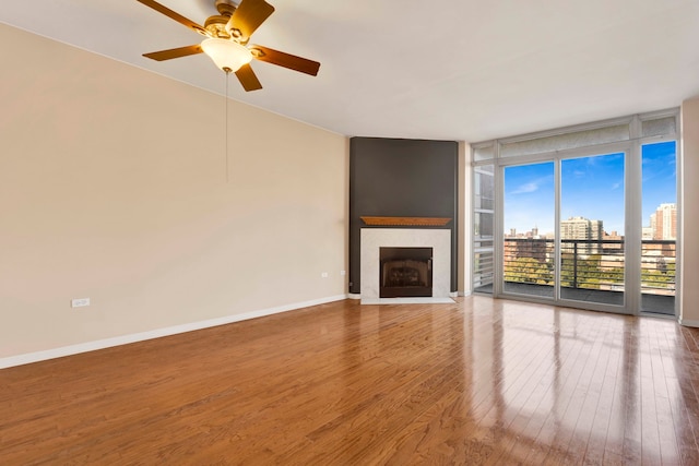 unfurnished living room featuring wood-type flooring, floor to ceiling windows, and ceiling fan