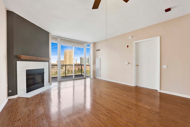 unfurnished living room featuring a premium fireplace, floor to ceiling windows, ceiling fan, and hardwood / wood-style flooring