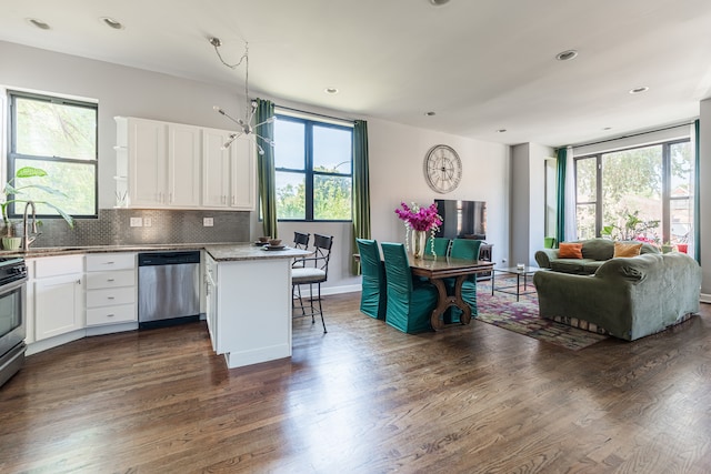 kitchen with white cabinets, appliances with stainless steel finishes, plenty of natural light, and a kitchen bar