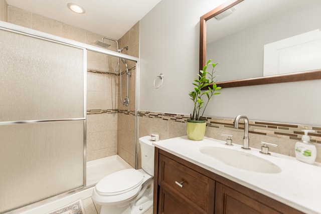 bathroom with tile walls, tile patterned flooring, a shower with door, vanity, and toilet