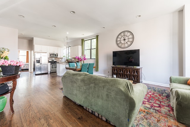 living room with a chandelier and dark wood-type flooring