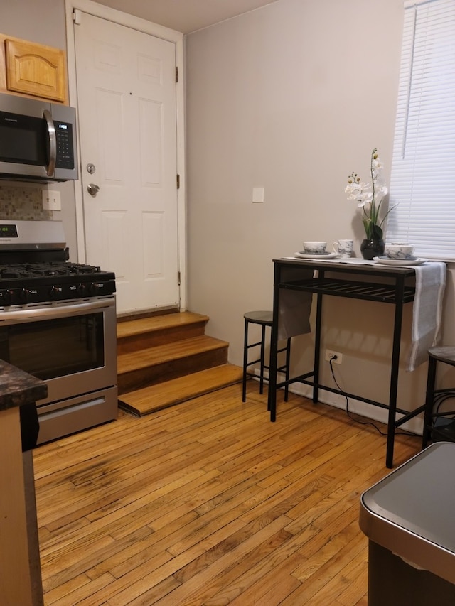 kitchen featuring light brown cabinetry, stainless steel appliances, and light wood-type flooring