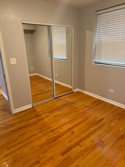 unfurnished bedroom featuring multiple windows, hardwood / wood-style flooring, and a closet