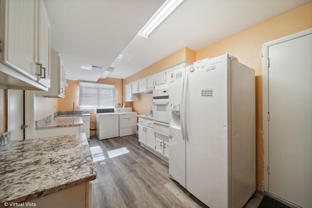 kitchen with light hardwood / wood-style flooring, white cabinets, white appliances, and light stone counters