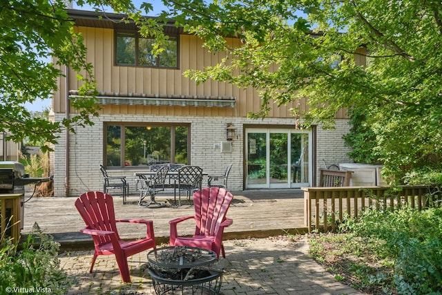 rear view of property with a deck and an outdoor fire pit