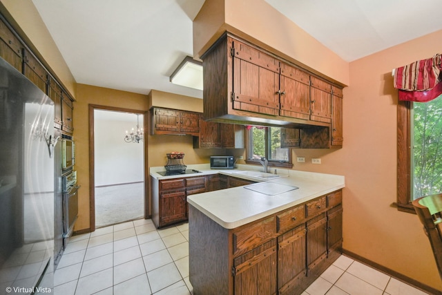 kitchen with stainless steel appliances, kitchen peninsula, light tile patterned floors, and sink