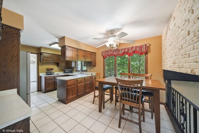 kitchen with ceiling fan, white refrigerator, dark brown cabinetry, and light tile patterned flooring