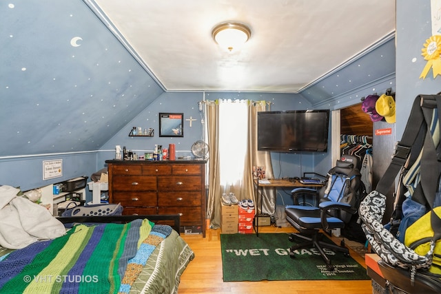 bedroom with light wood-type flooring, vaulted ceiling, and a closet