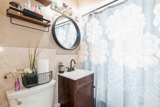 bathroom featuring walk in shower, vanity, tile walls, and toilet