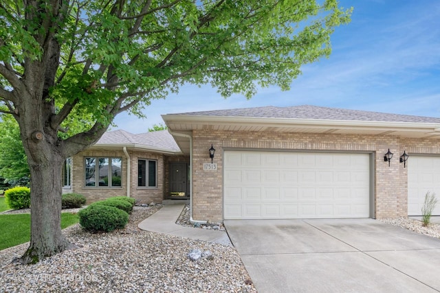 ranch-style home with brick siding, concrete driveway, roof with shingles, and an attached garage